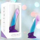 The Avant D16 Purple Haze 6.5" Slim Non-Porous Silicone Dildo, featuring a hand-sculpted, curved form in purple, blue, and pink platinum cured silicone, is shown inside Avant packaging and displayed against a pastel bokeh background.